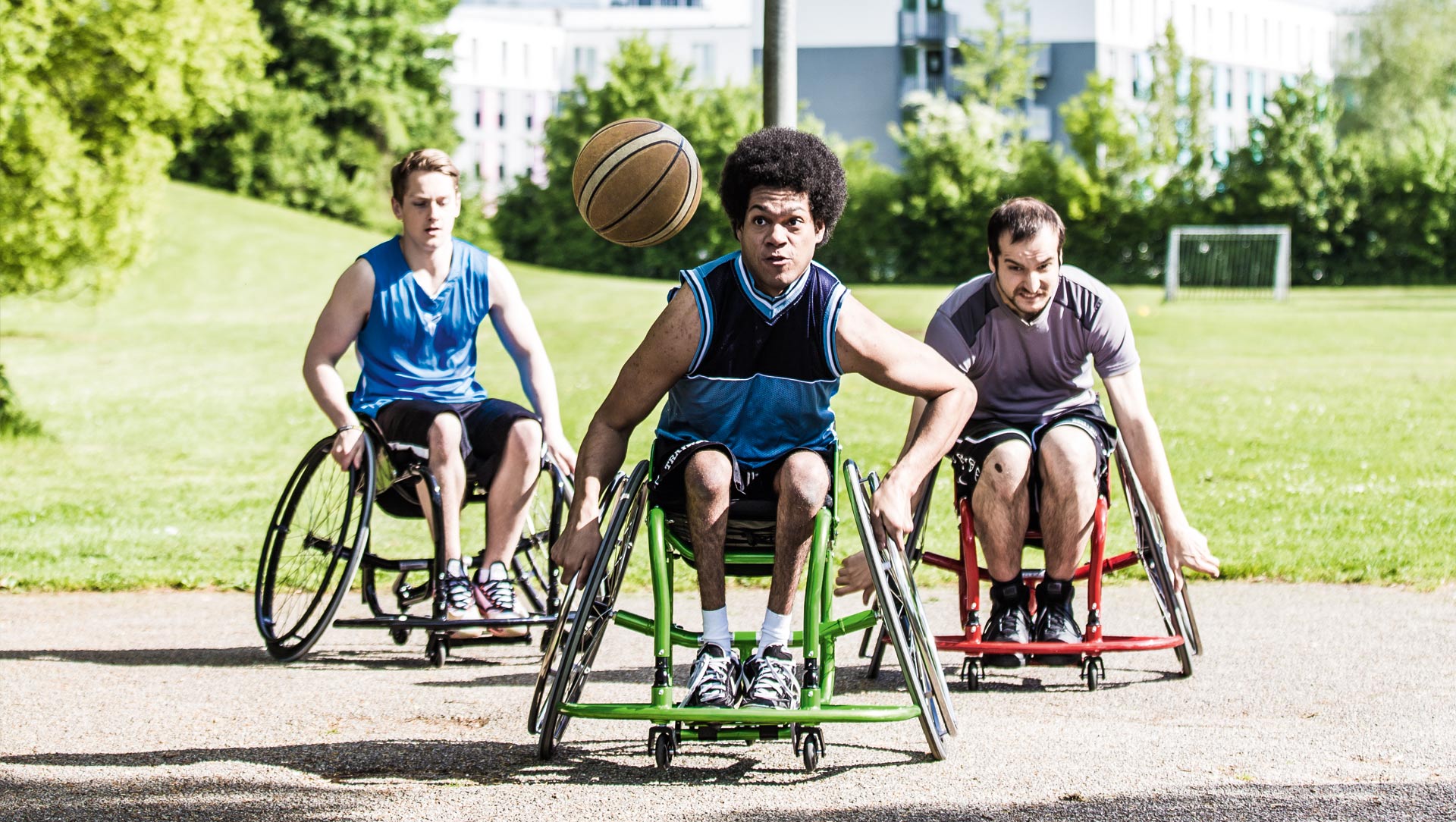 Drei Rollstuhlfahrer spielen Basketball